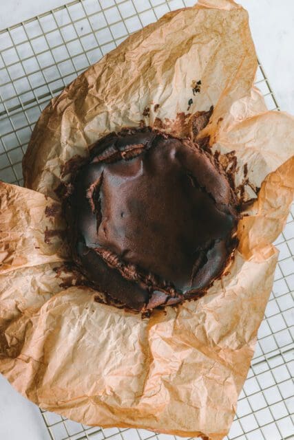 Baked chocolate basque cheesecake with paper peeled away.