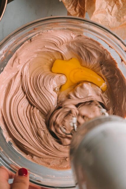 Beating eggs into chocolate cheesecake batter