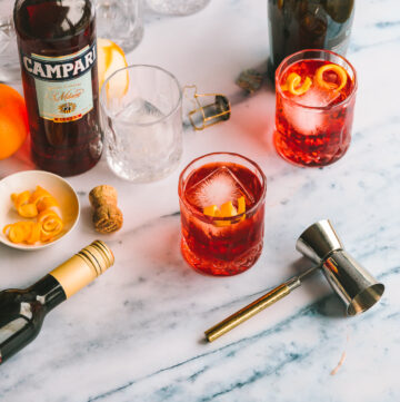 Two glasses of Negroni Sbagliato on a marble countertop.