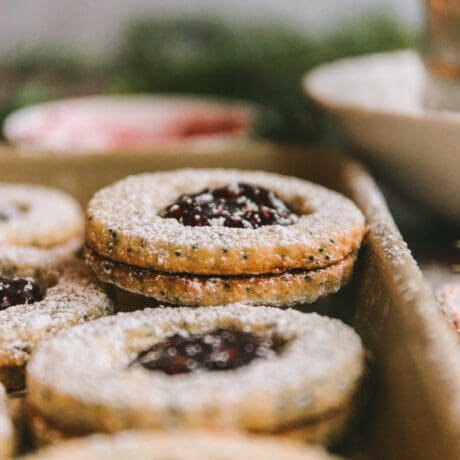 Raspberry linzer cookie recipe stacked on baking sheet.