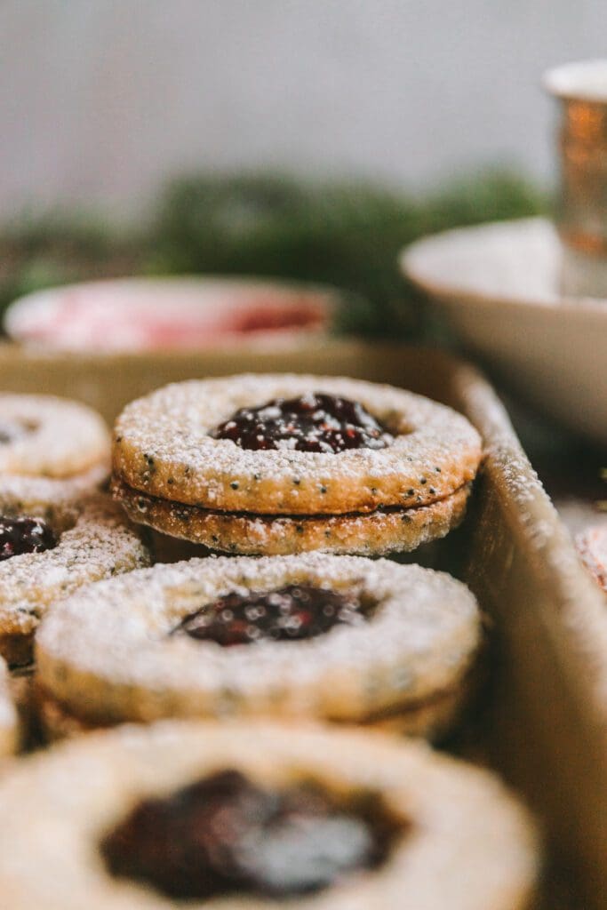 Raspberry linzer cookie recipe stacked on baking sheet.