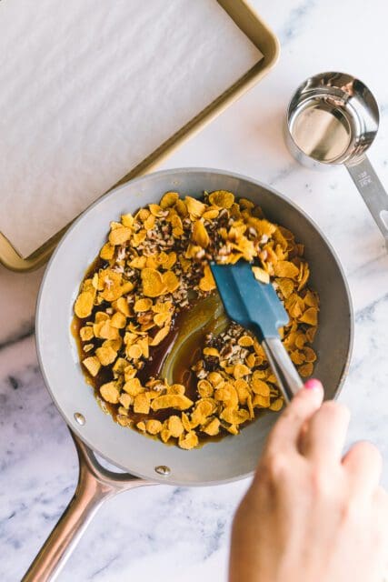 mixing cereal brittle on a marble countertop in a pan