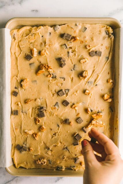 sprinkling toasted walnuts and chocolate chips on blondie batter