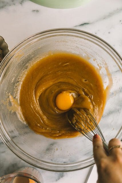 whisking in an egg to brown sugar and melted butter for blondie recipe