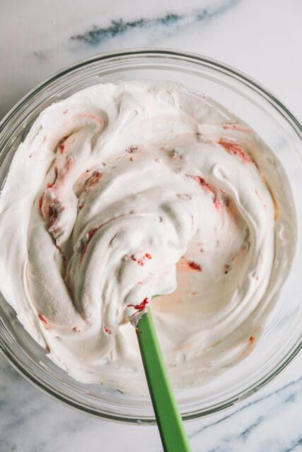 mixing a swirled raspberry whipped cream to top the angel food cake