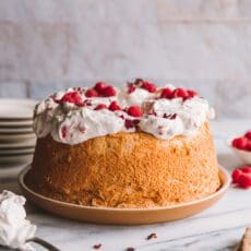 a table with a finished angel food cake recipe, raspberries and plates