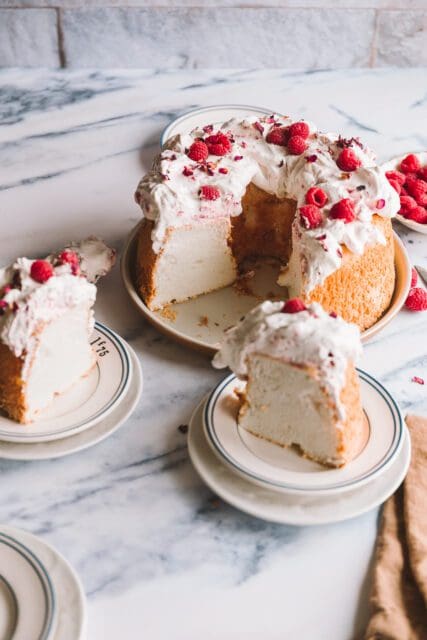 angel food cake on a table with two slices sitting aside it on plates