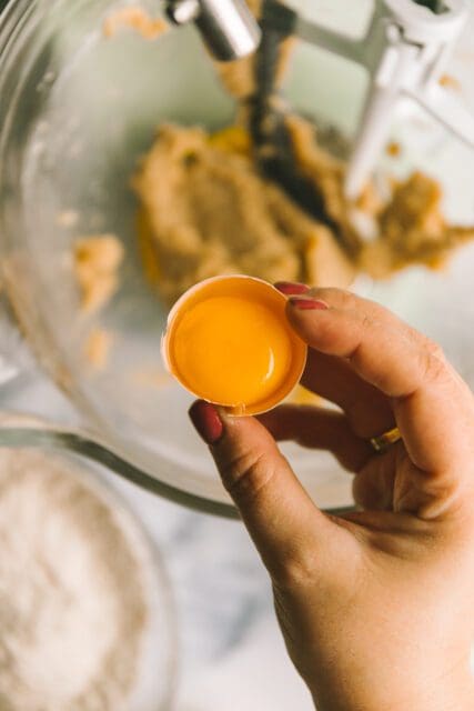close up of a separated egg yolk with cookie batter in a bowl on the counter