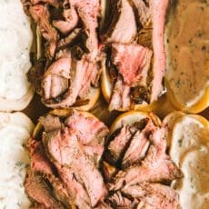 putting the final touch, the flank steak, on the French dip sandwich