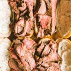 putting the final touch, the flank steak, on the French dip sandwich