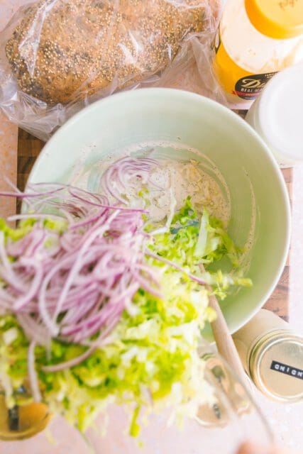 adding onions and cabbage to make a slaw for the tomato sandwich