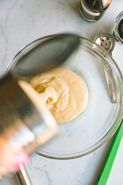 pouring sweetened condensed milk into a bowl for coffee ice cream