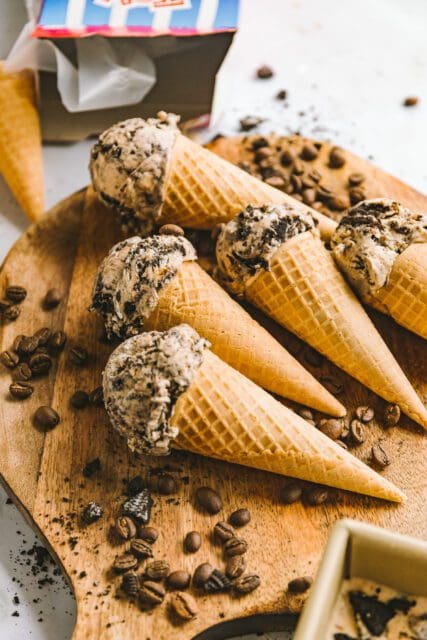 ice cream cones on a wooden board surrounded by coffee beans