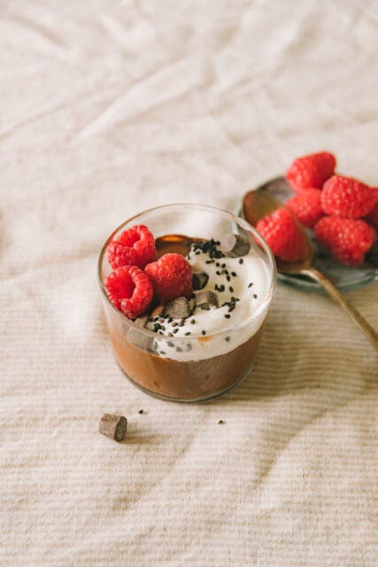 overhead shot of chocolate pudding with raspberries on a plate next to it