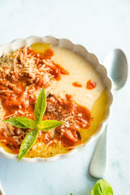 close up of baked polenta with olive oil, burst tomatoes, and basil