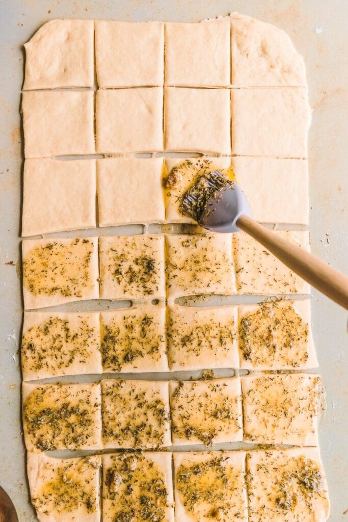 Brushing pull apart garlic bread with herb butter.